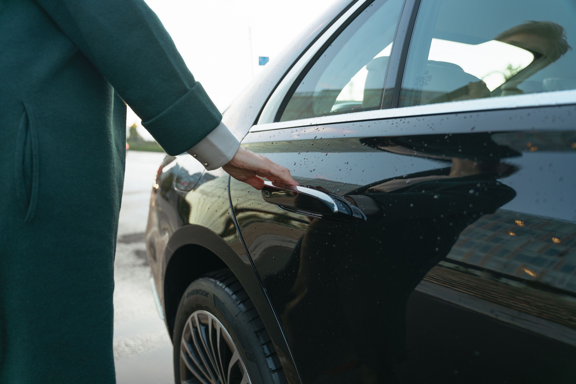 A woman opens a car door of a premier class car